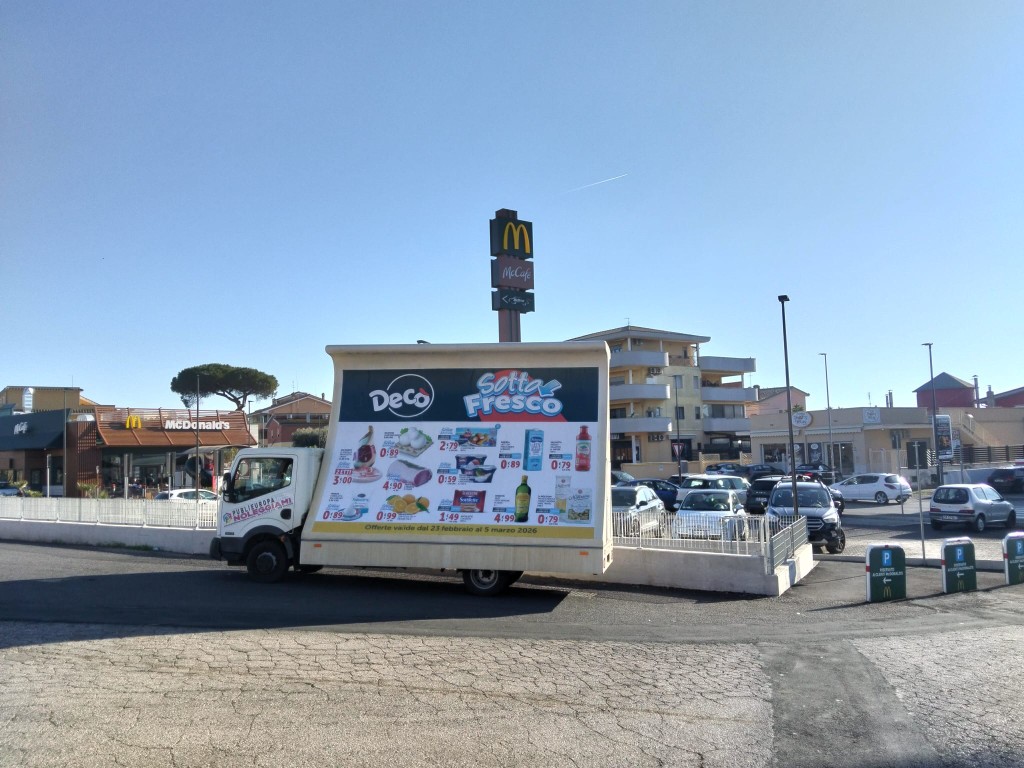 Camion con pubblicità Decò in area commerciale ad alta affluenza.